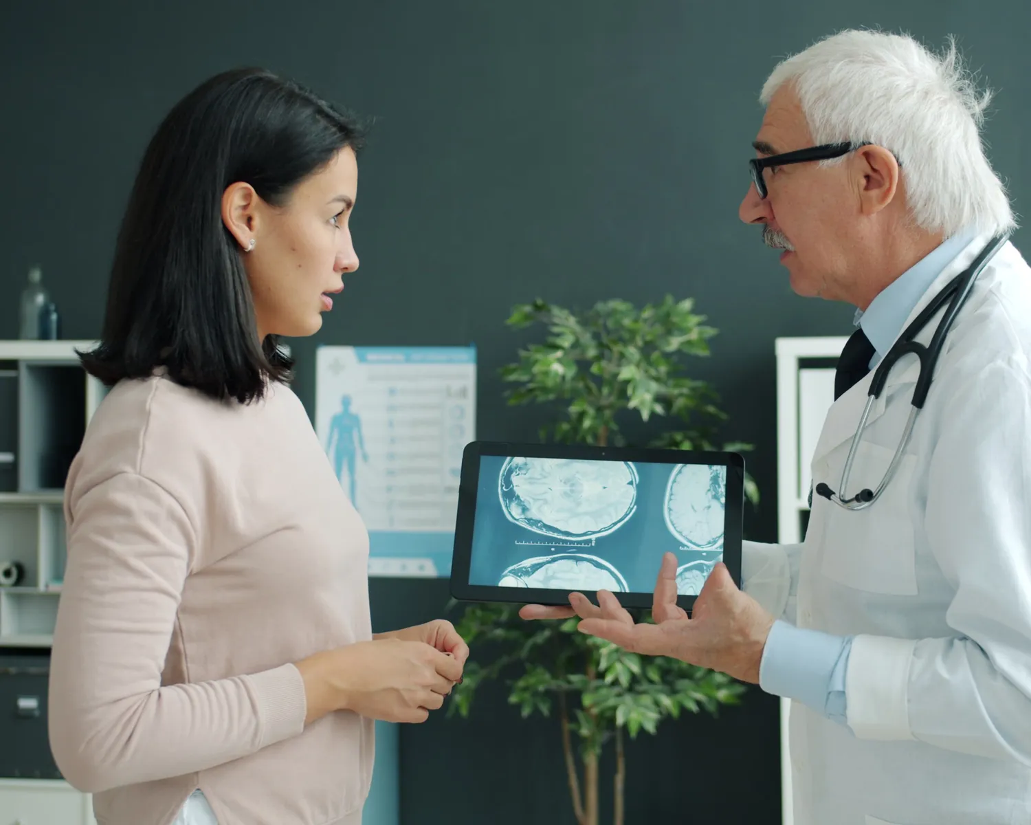 A doctor shows a woman brain scans on a tablet and talks her through them.