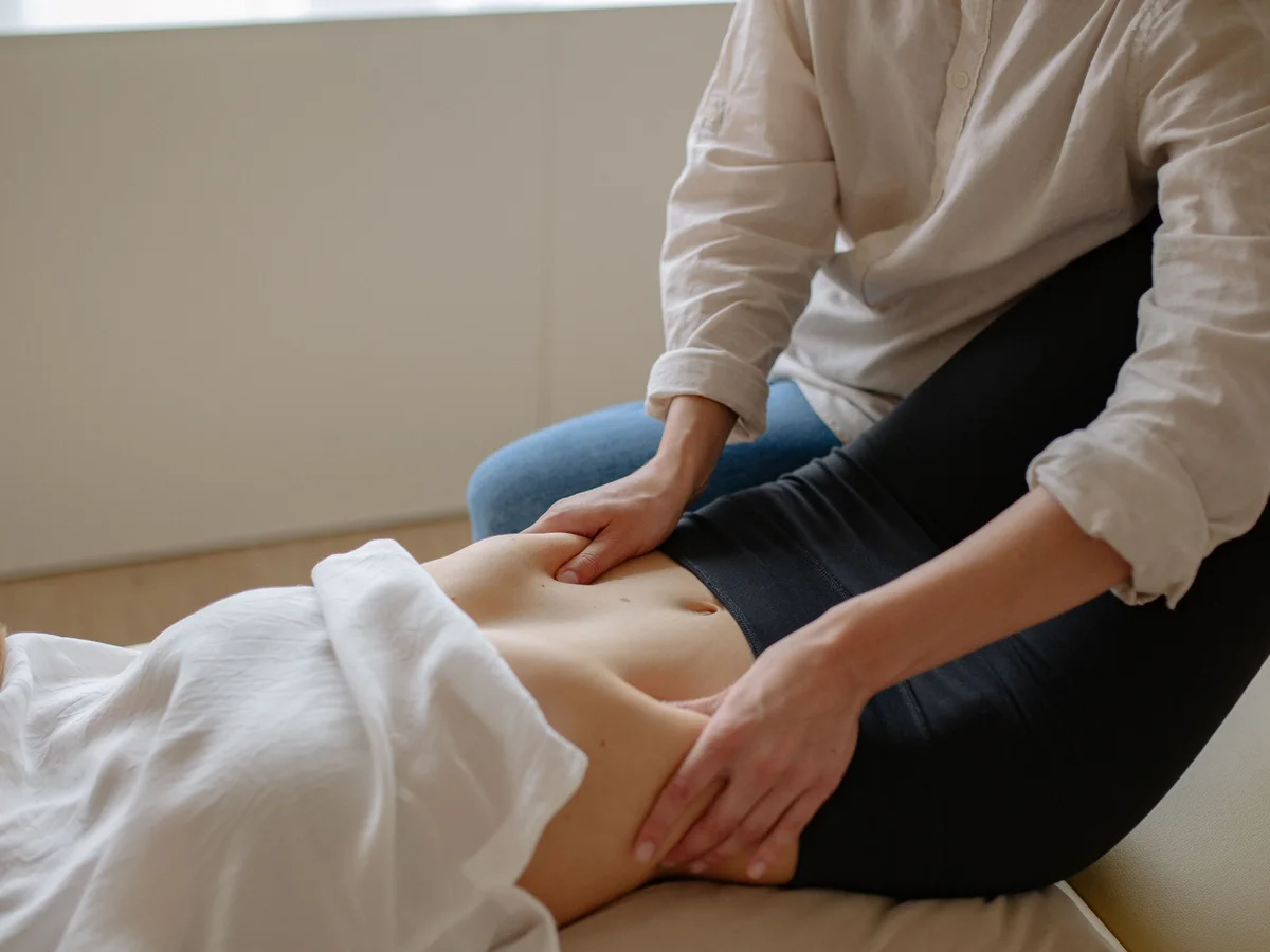 A practitioner gently examines a woman's abdomen.