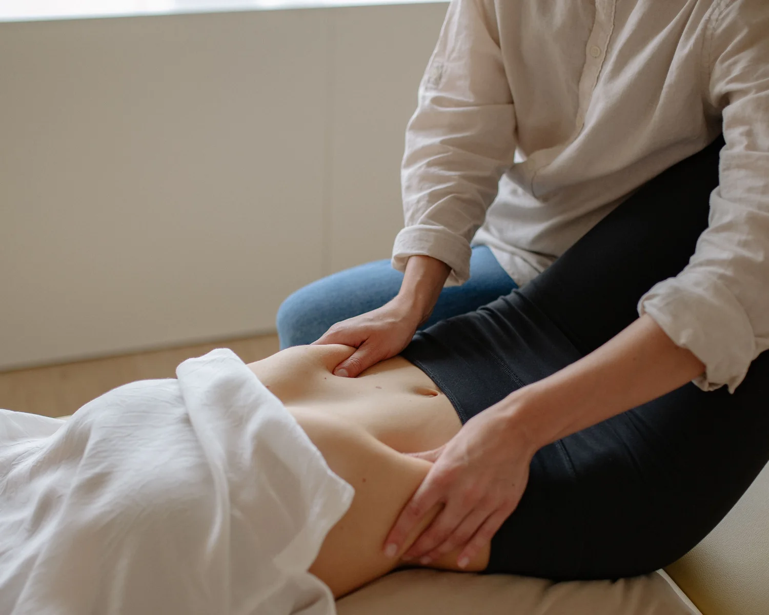 A practitioner gently examines a woman's abdomen.