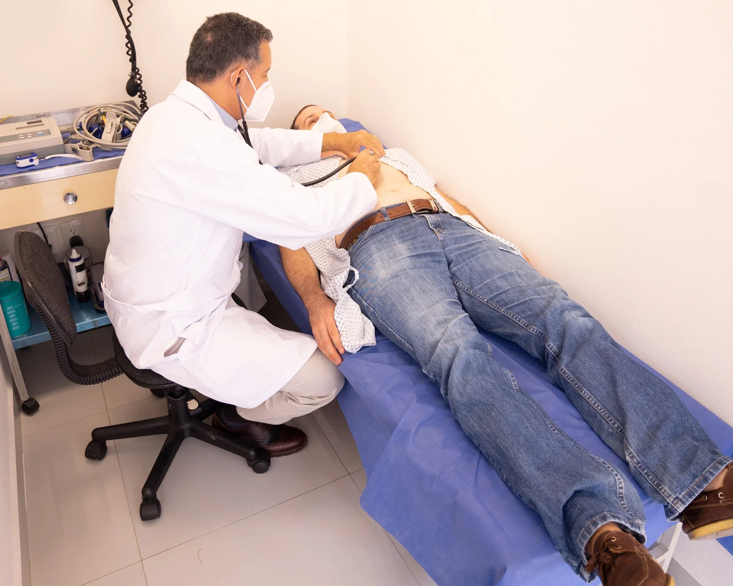 A clinician examines a man lying on an examination table.