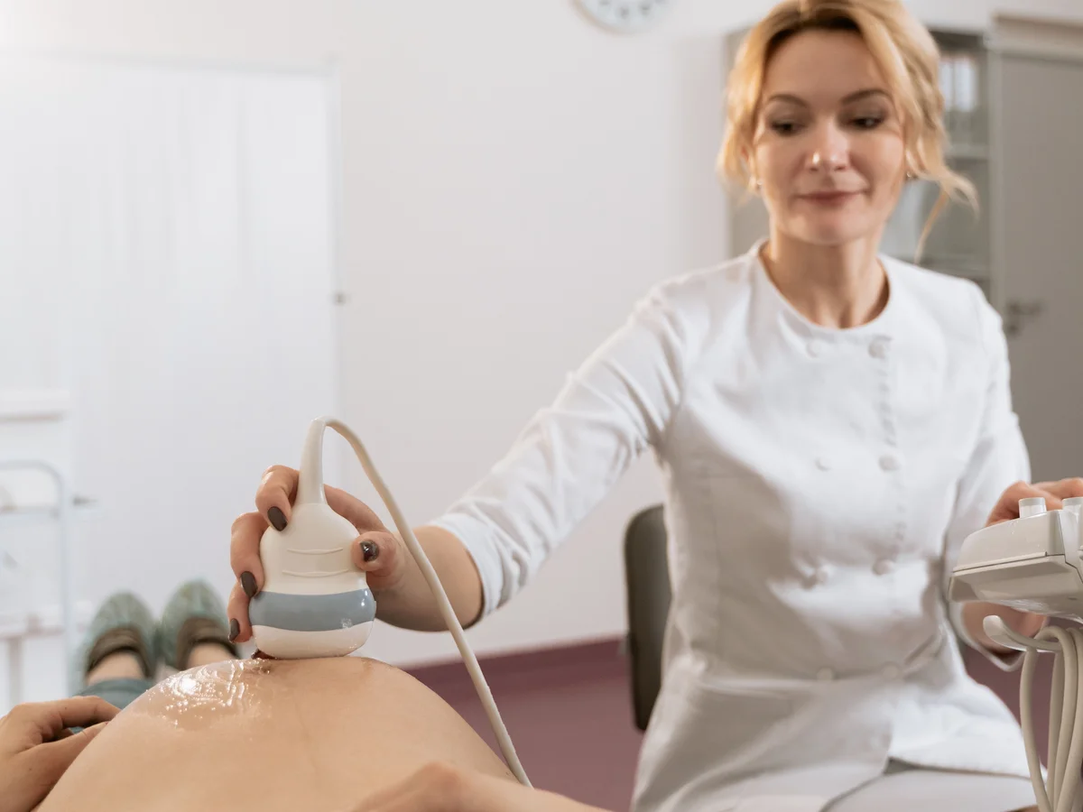 A clinician uses an ultrasound probe during an abdominal examination.