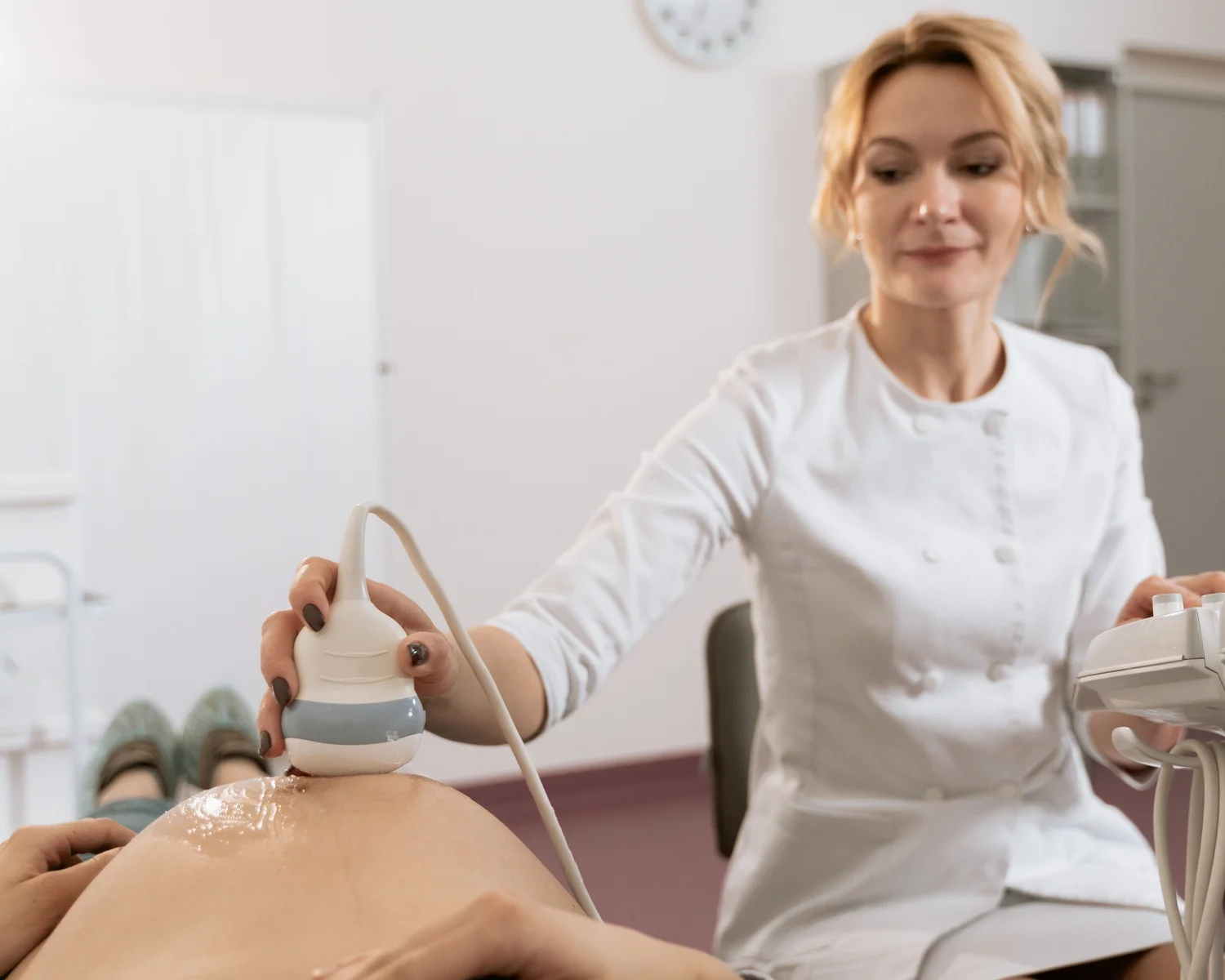 A clinician uses an ultrasound probe during an abdominal examination.
