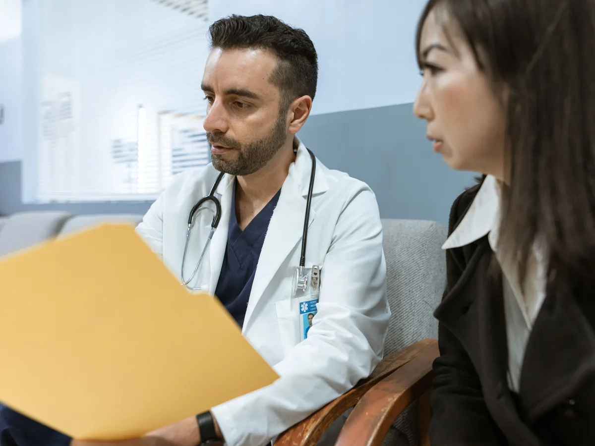 A doctor reviews a patient's records with her during a consultation.