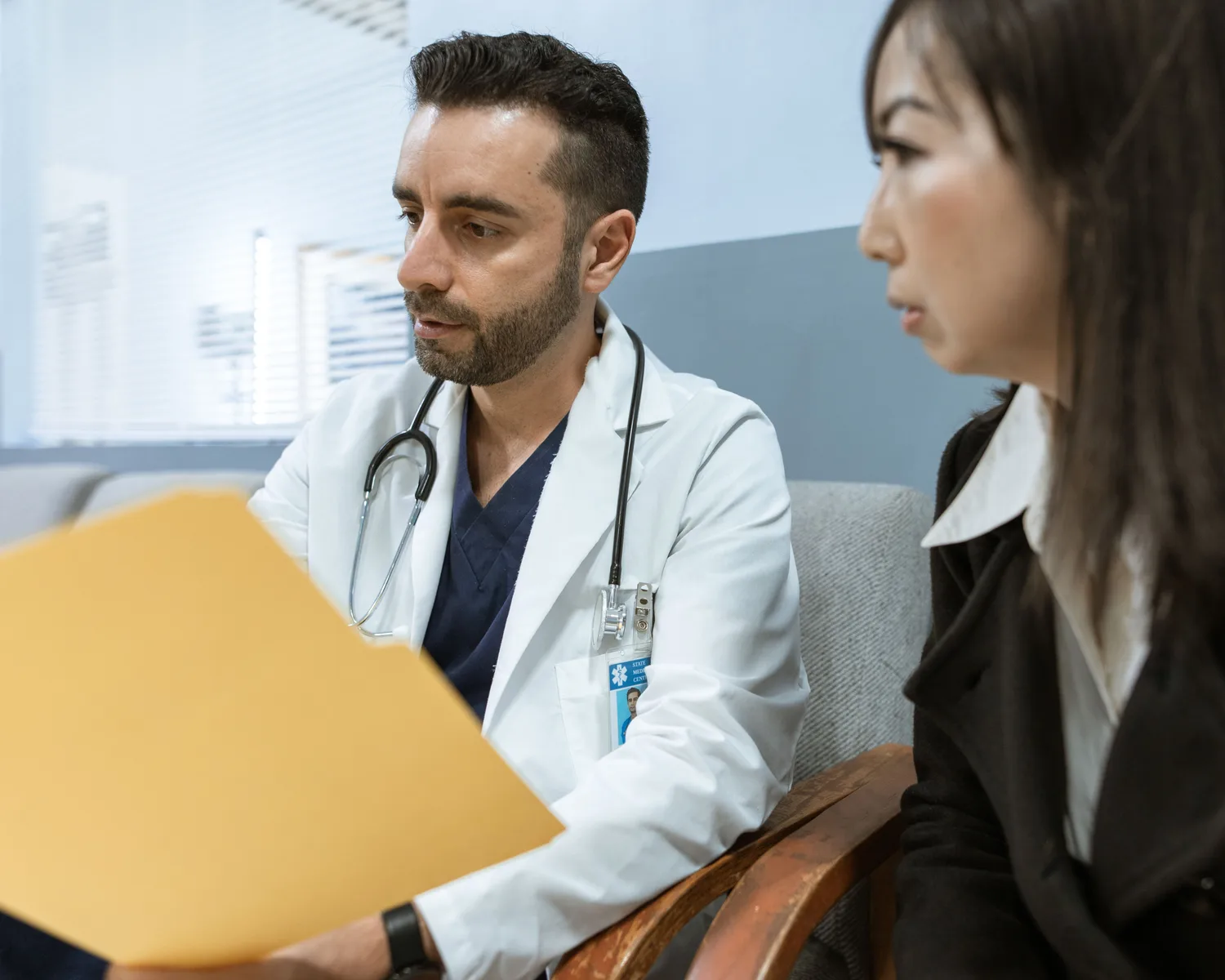 A doctor reviews a patient's records with her during a consultation.