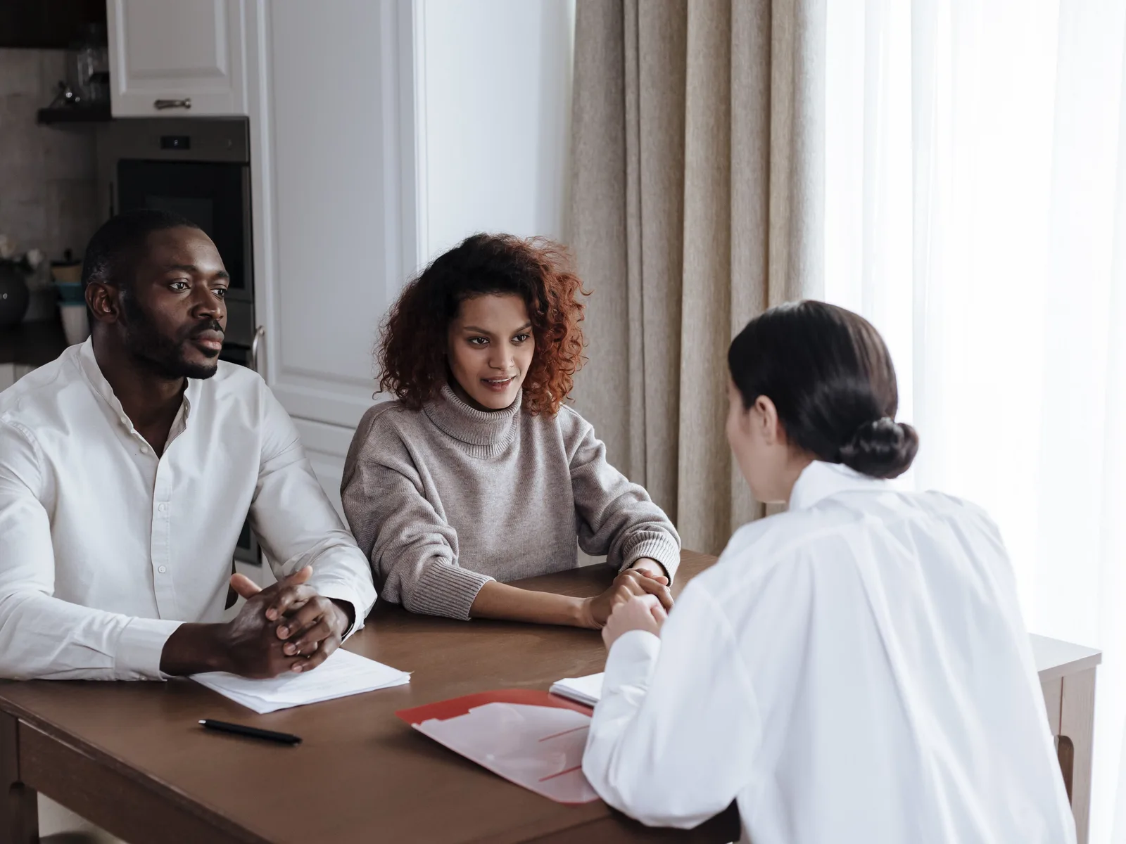 A social worker goes over documents with a couple at their kitchen table.