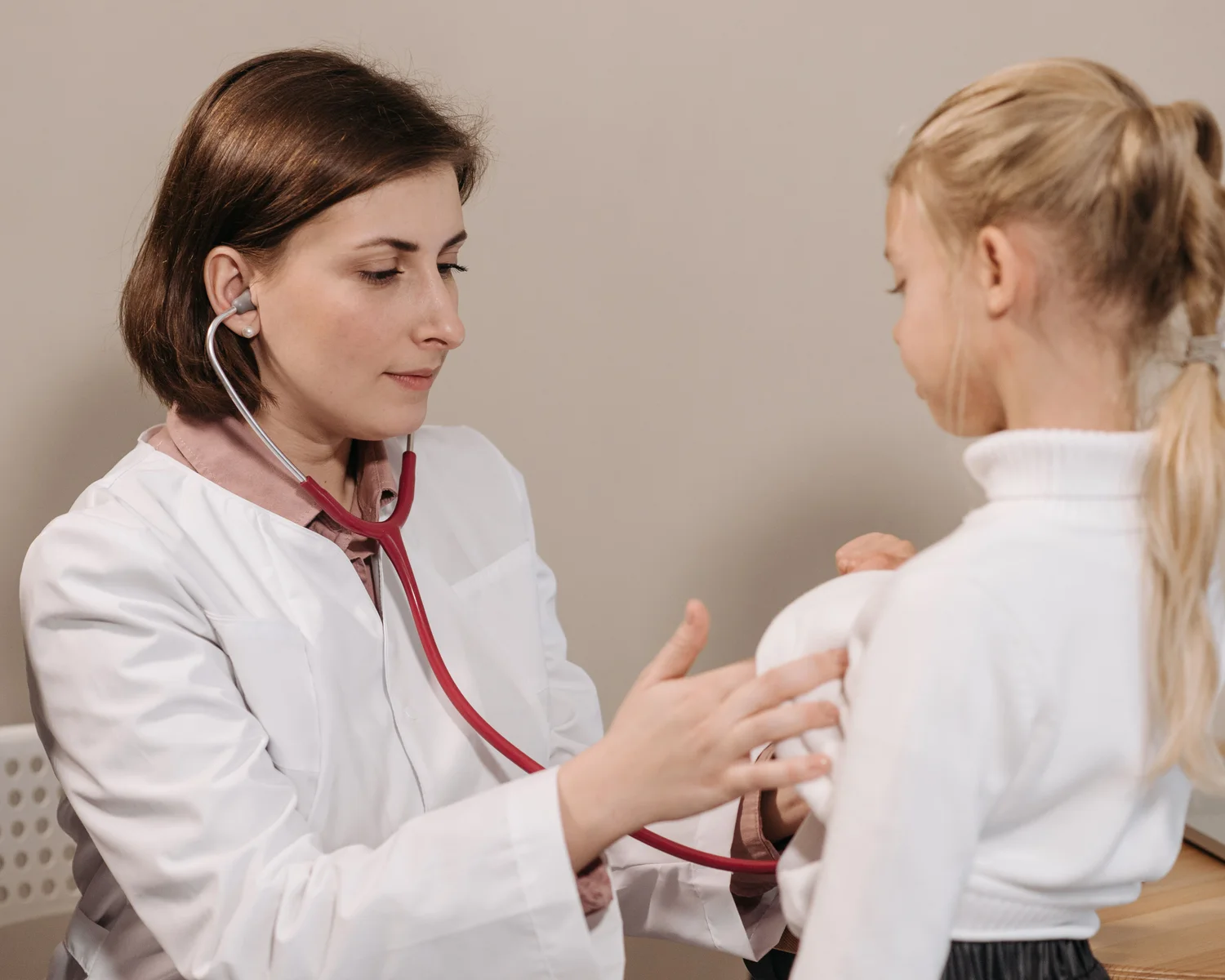 A clinician uses a stethoscope to examine a child during a check-up.