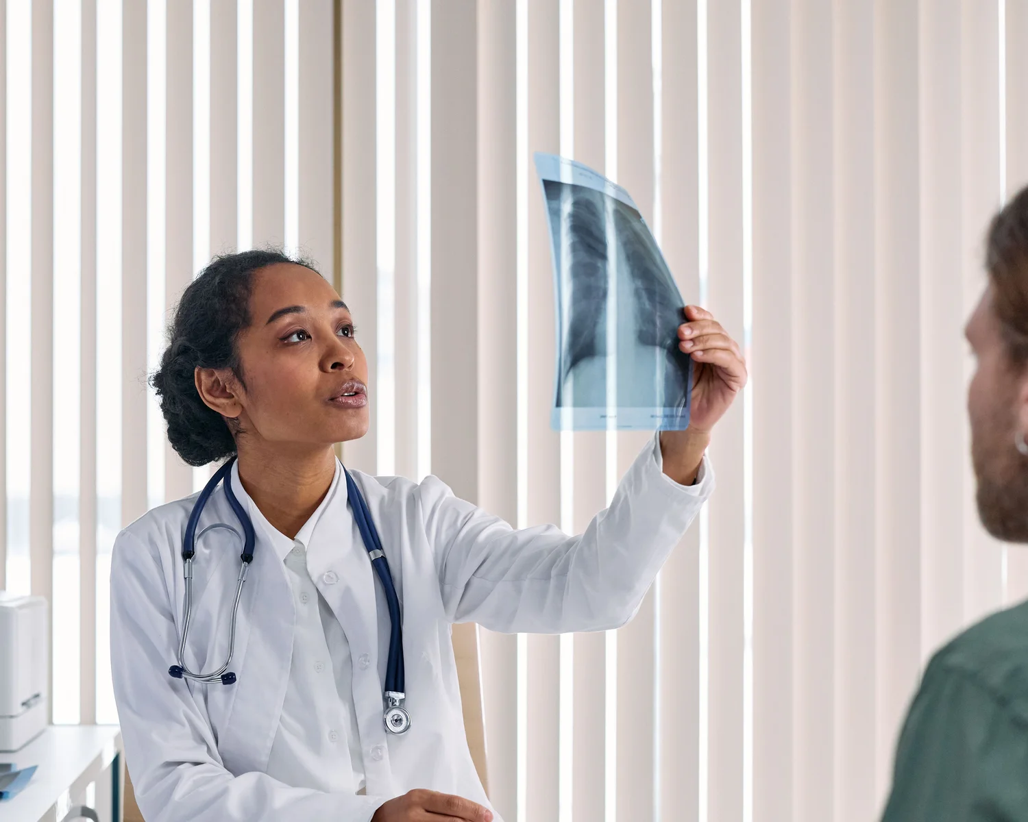 A clinician explains an X-ray to a seated man.