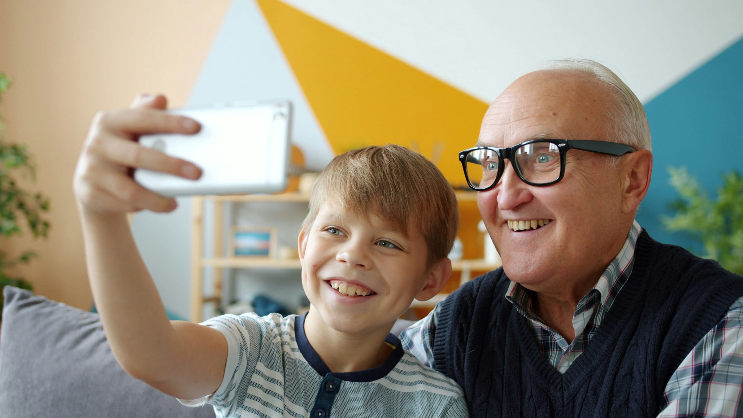 A grandfather and his grandson smiling as they take a selfie together