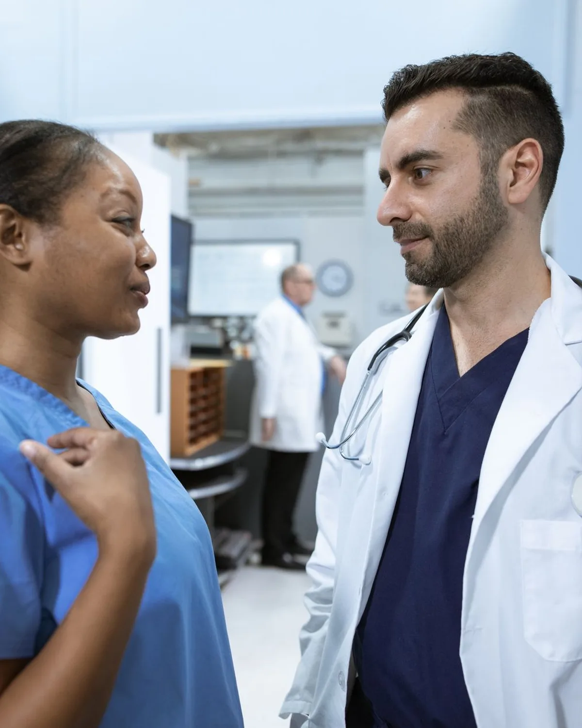 Clinicians talk through a patient's care in a hospital hallway.