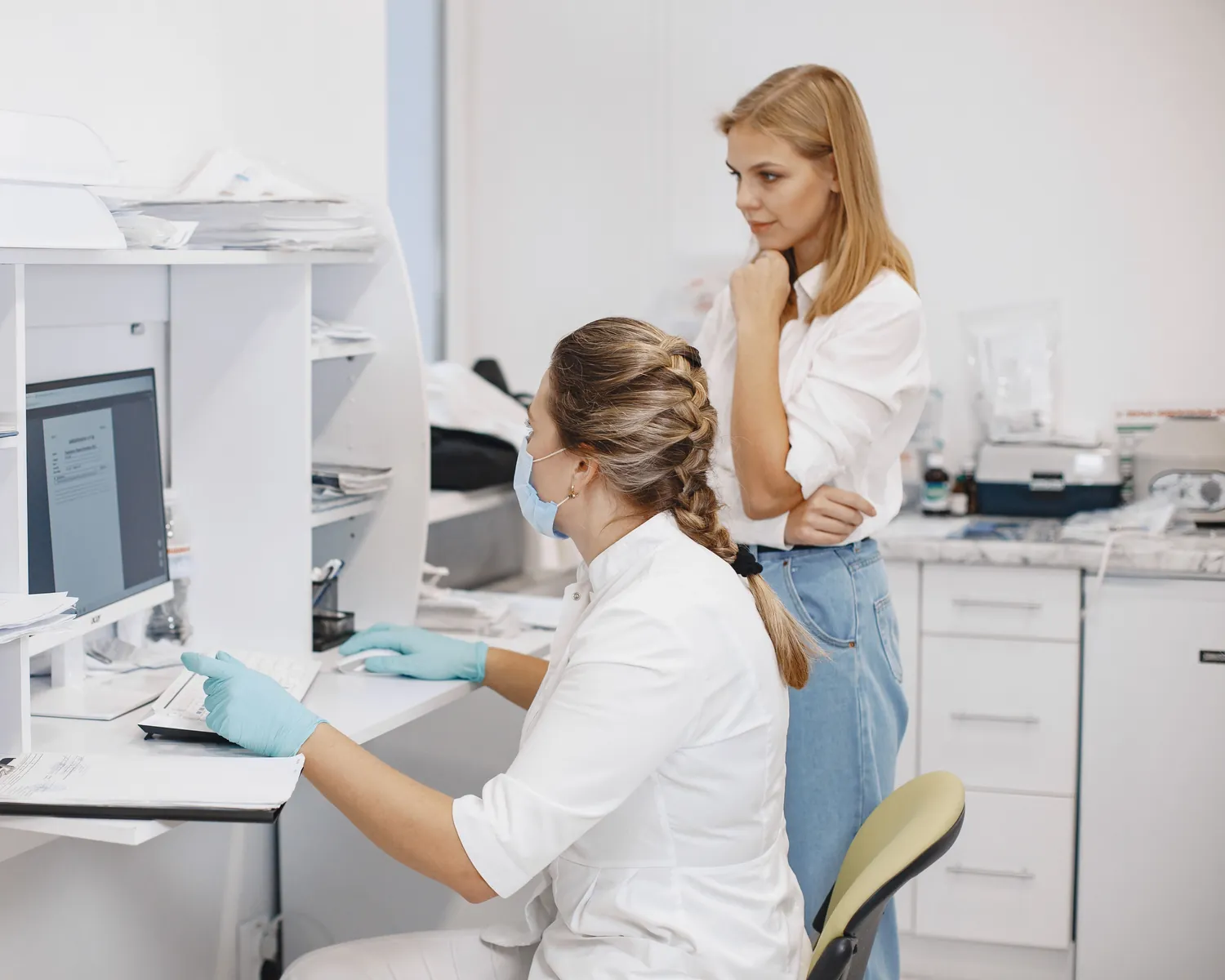 A clinician and a colleague review information on a computer screen together.
